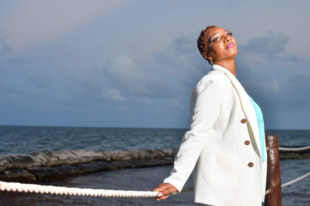 A woman in white jacket holding a rope near body of water.