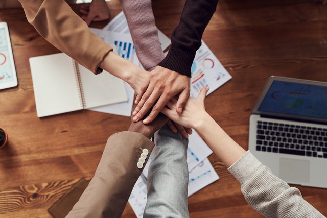 A group of people holding hands on top of papers.